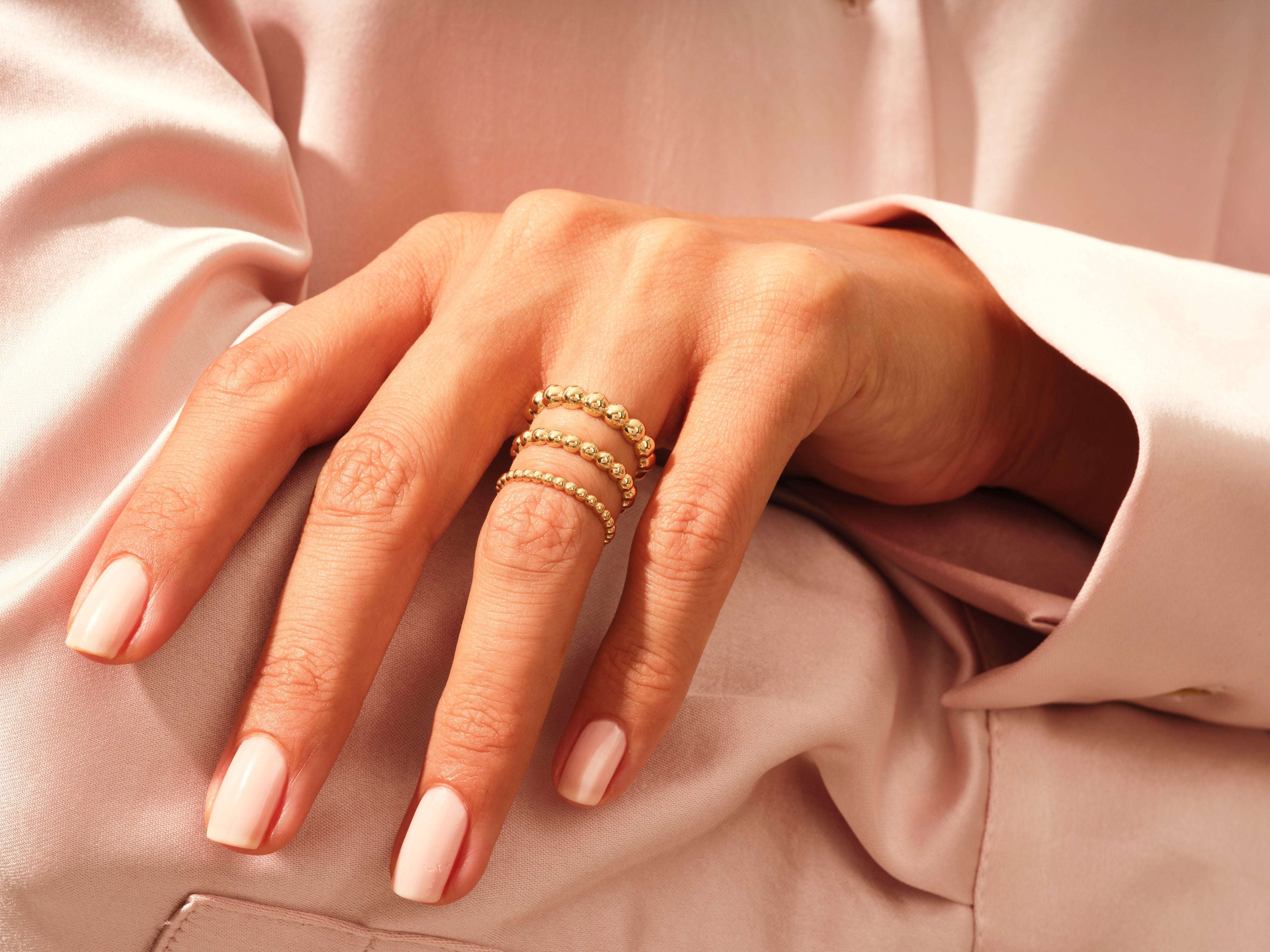 Gold beaded stackable rings on a hand, jewelry