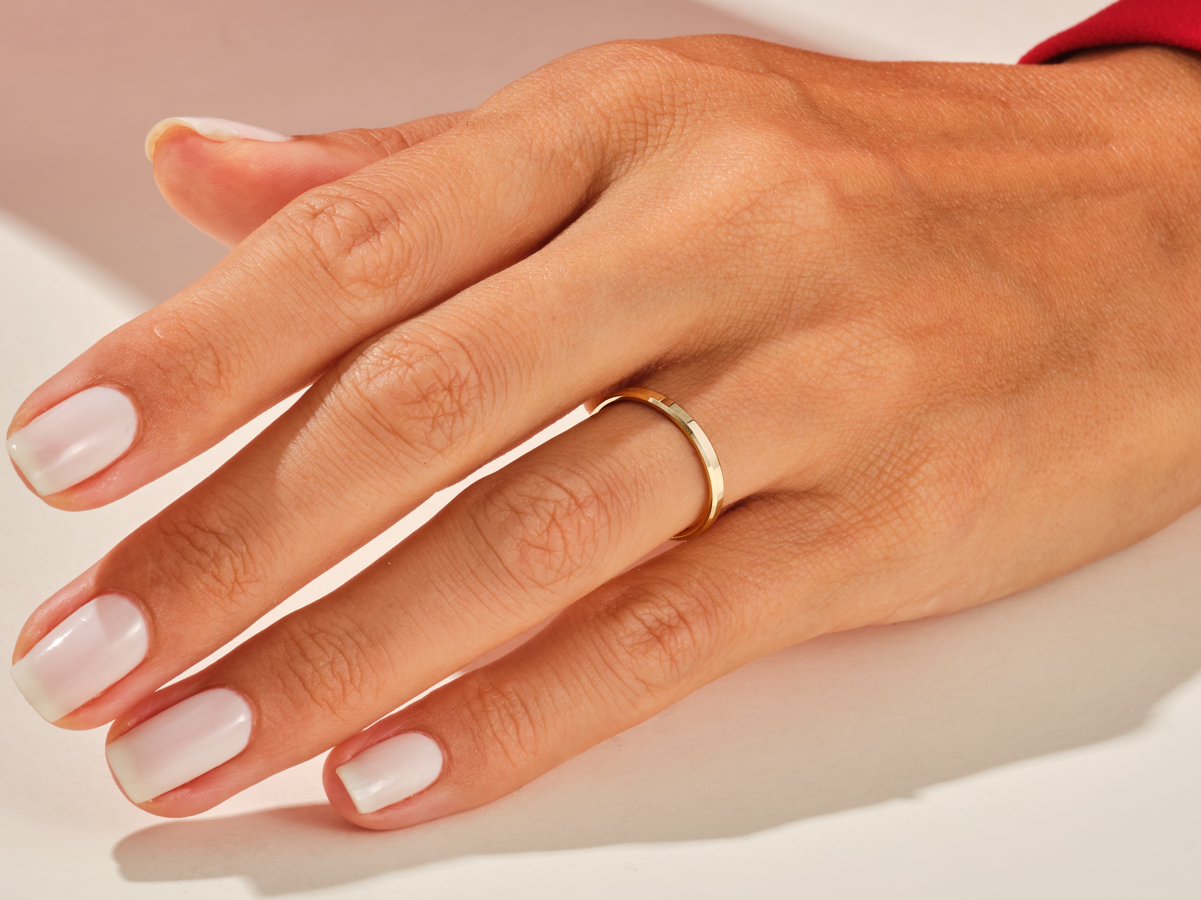 Gold band ring on a hand with manicured nails