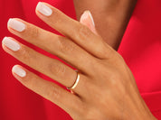 Gold wedding band on hand with white nails, jewelry product