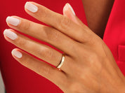 Gold wedding band on a hand with white nails, jewelry