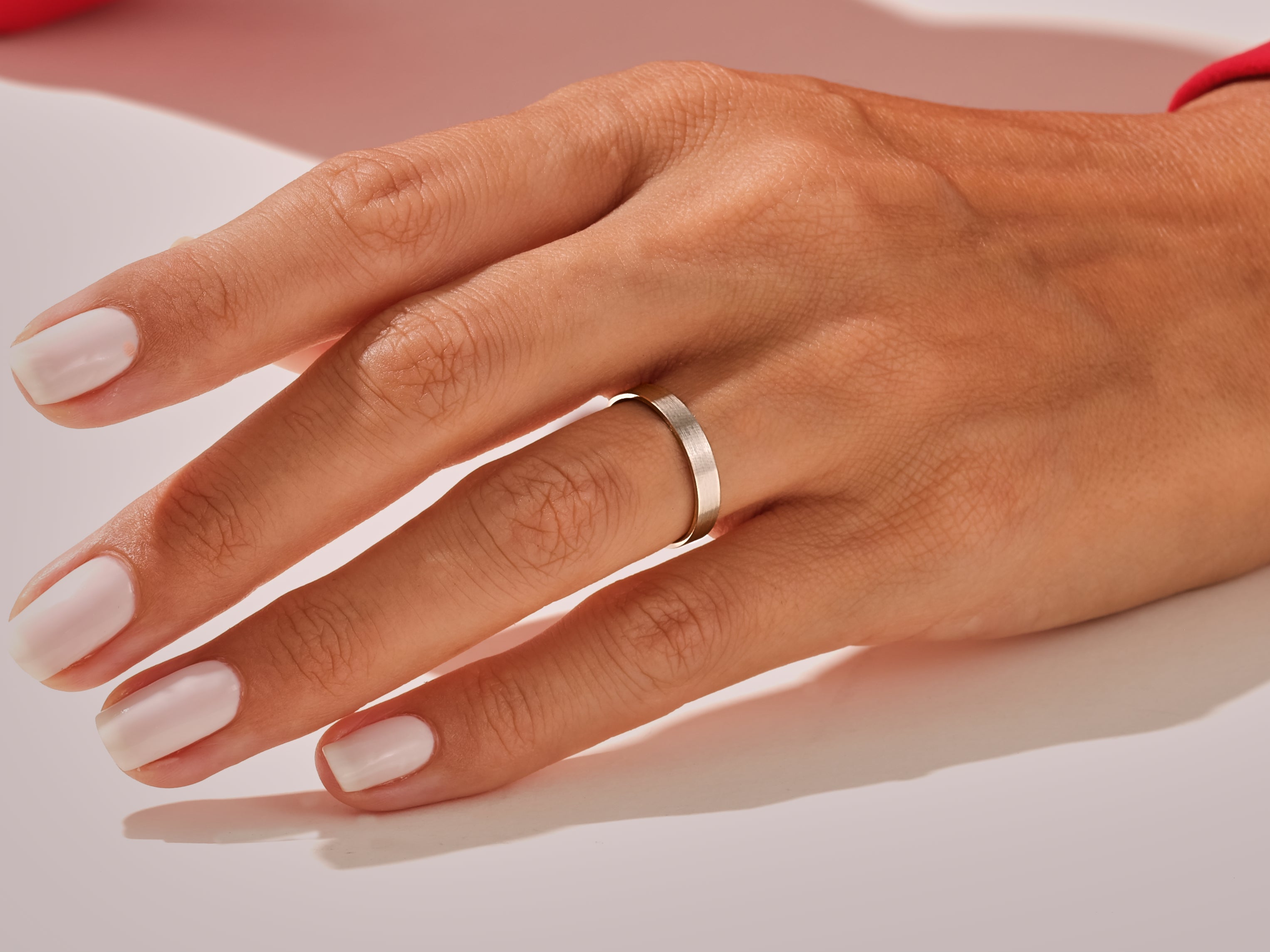 Minimalist silver ring on a hand with white nails, jewelry product