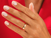 Gold band ring on a hand with white nails, jewelry