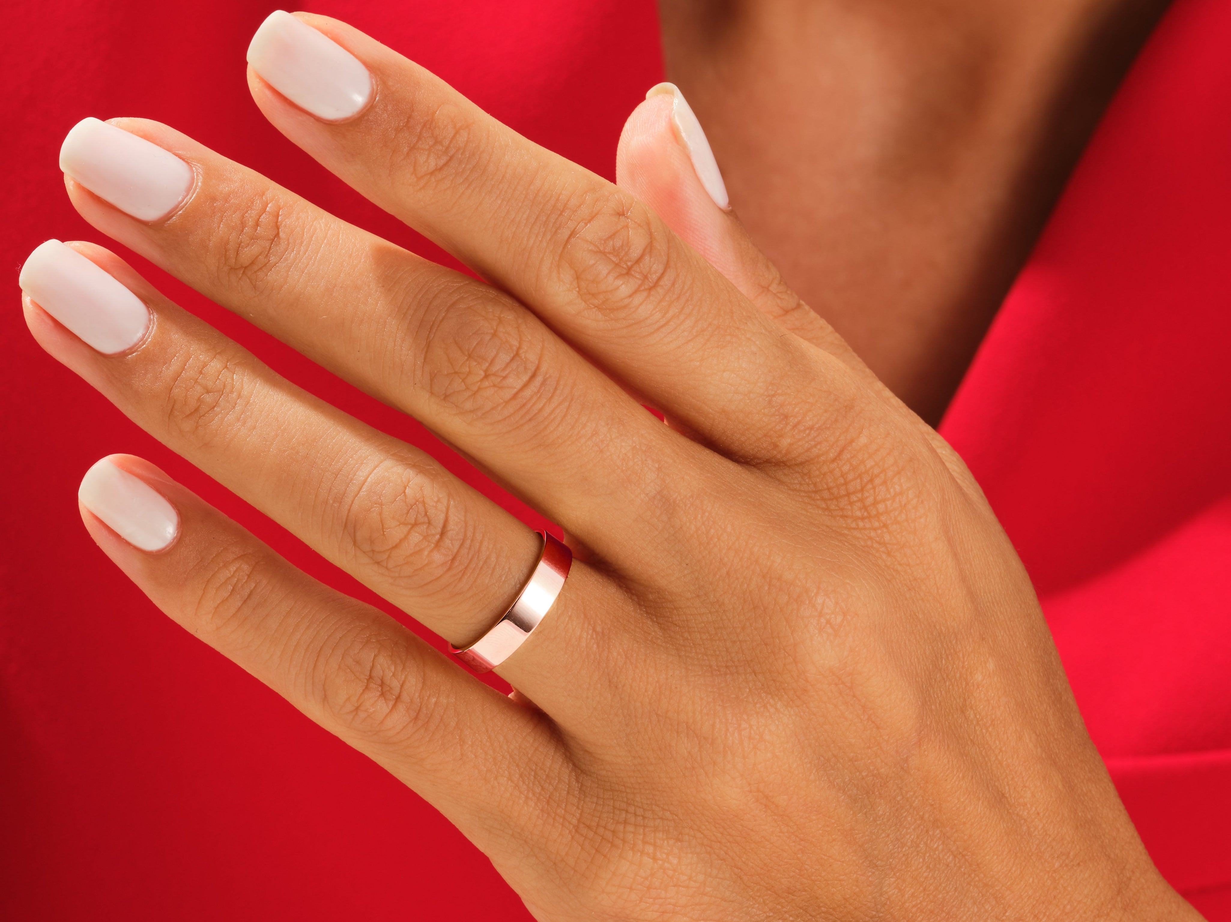 Rose gold band ring on a hand with white nails, jewelry