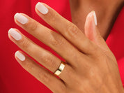 Gold wedding band on a hand with white nails, jewelry