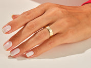 Gold band ring on a hand with manicured nails