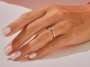 Minimalist silver band ring on a hand with white nails