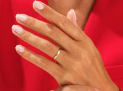 Gold wedding band on a hand with light nail polish, jewelry