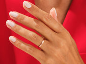 Rose gold band ring on a hand with white nails