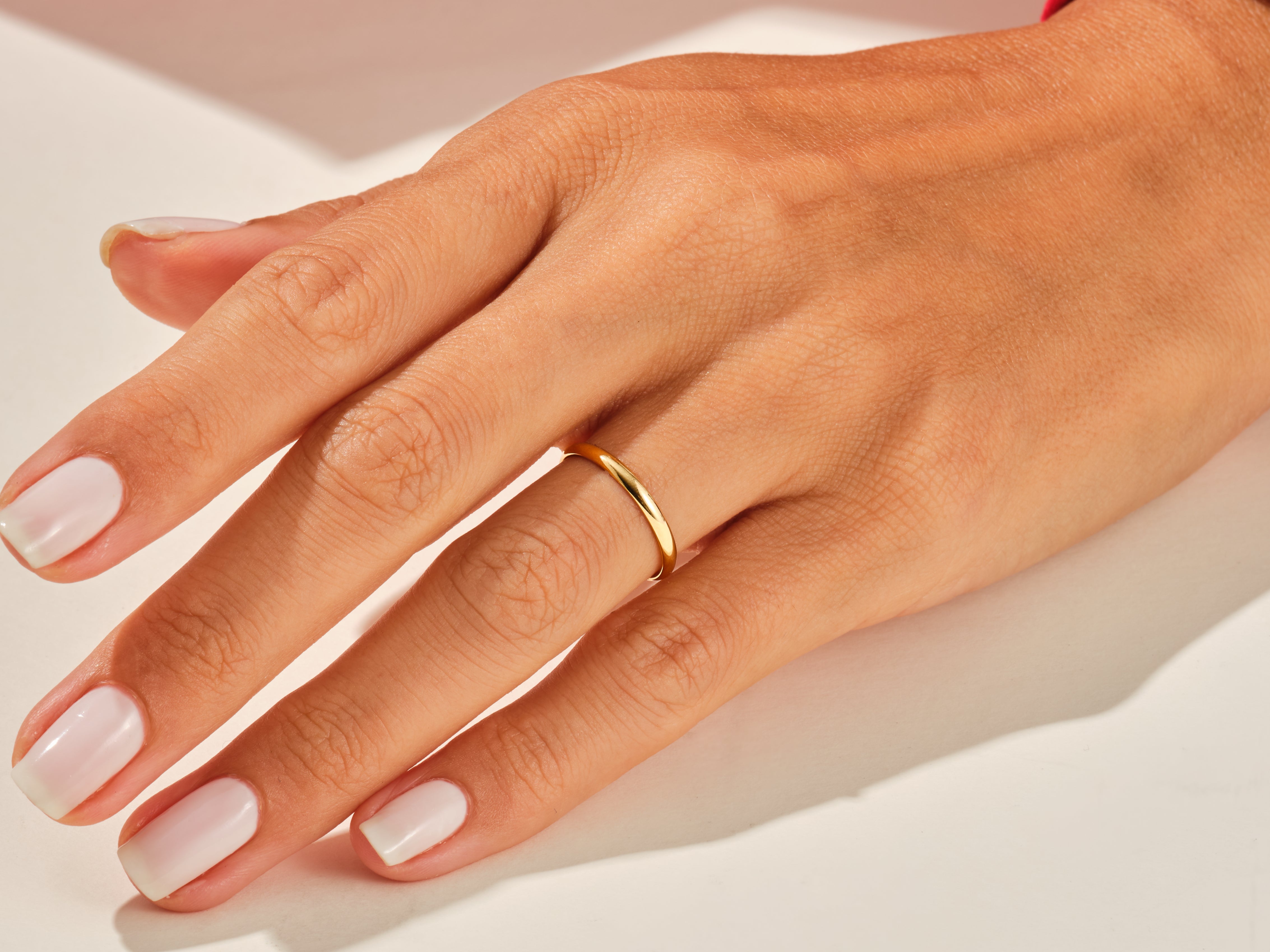 Gold band ring on a woman's finger, jewelry product photography