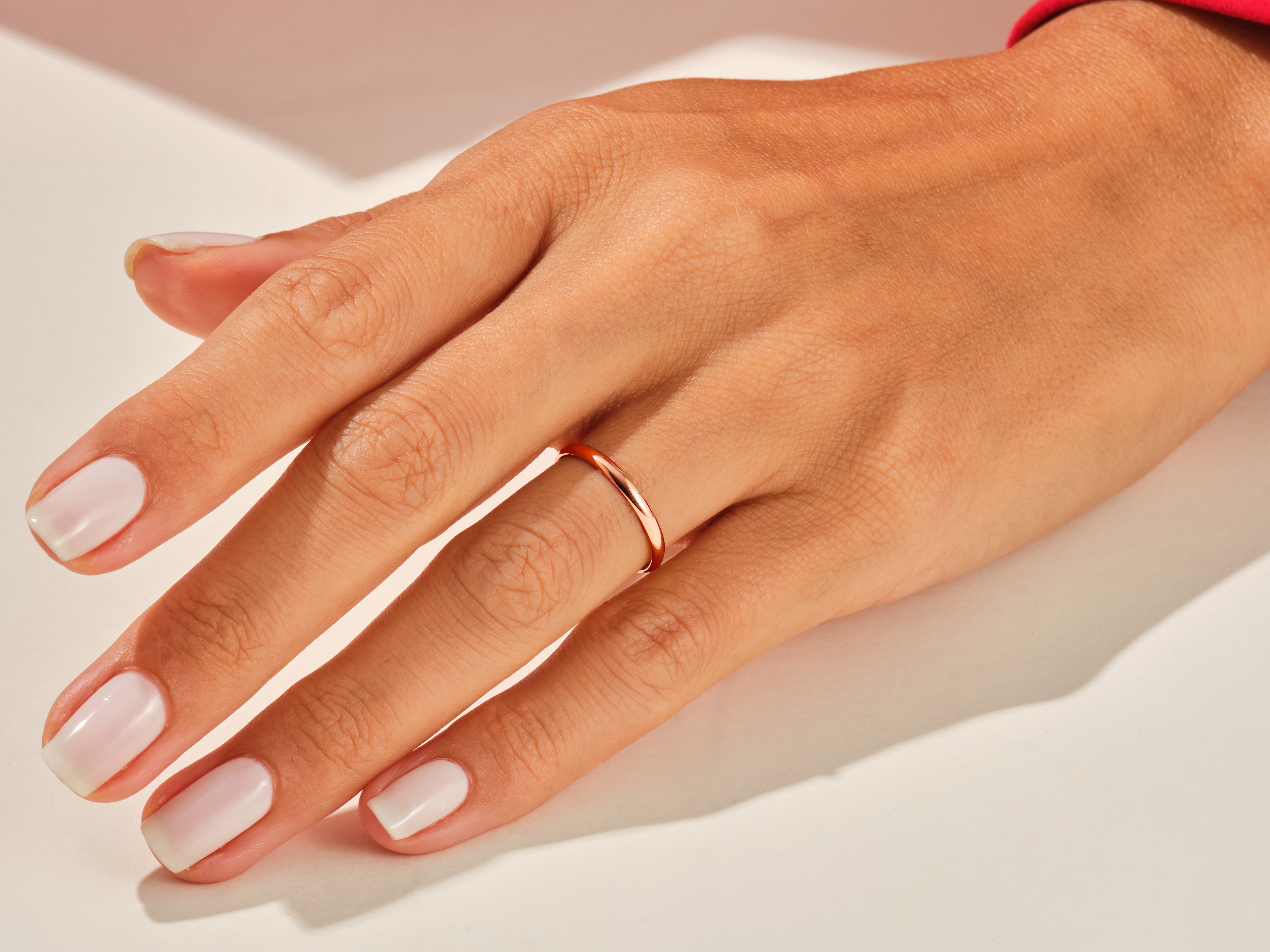 Rose gold band ring on a manicured hand