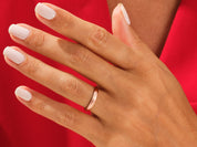 Rose gold wedding band on a hand with white nails