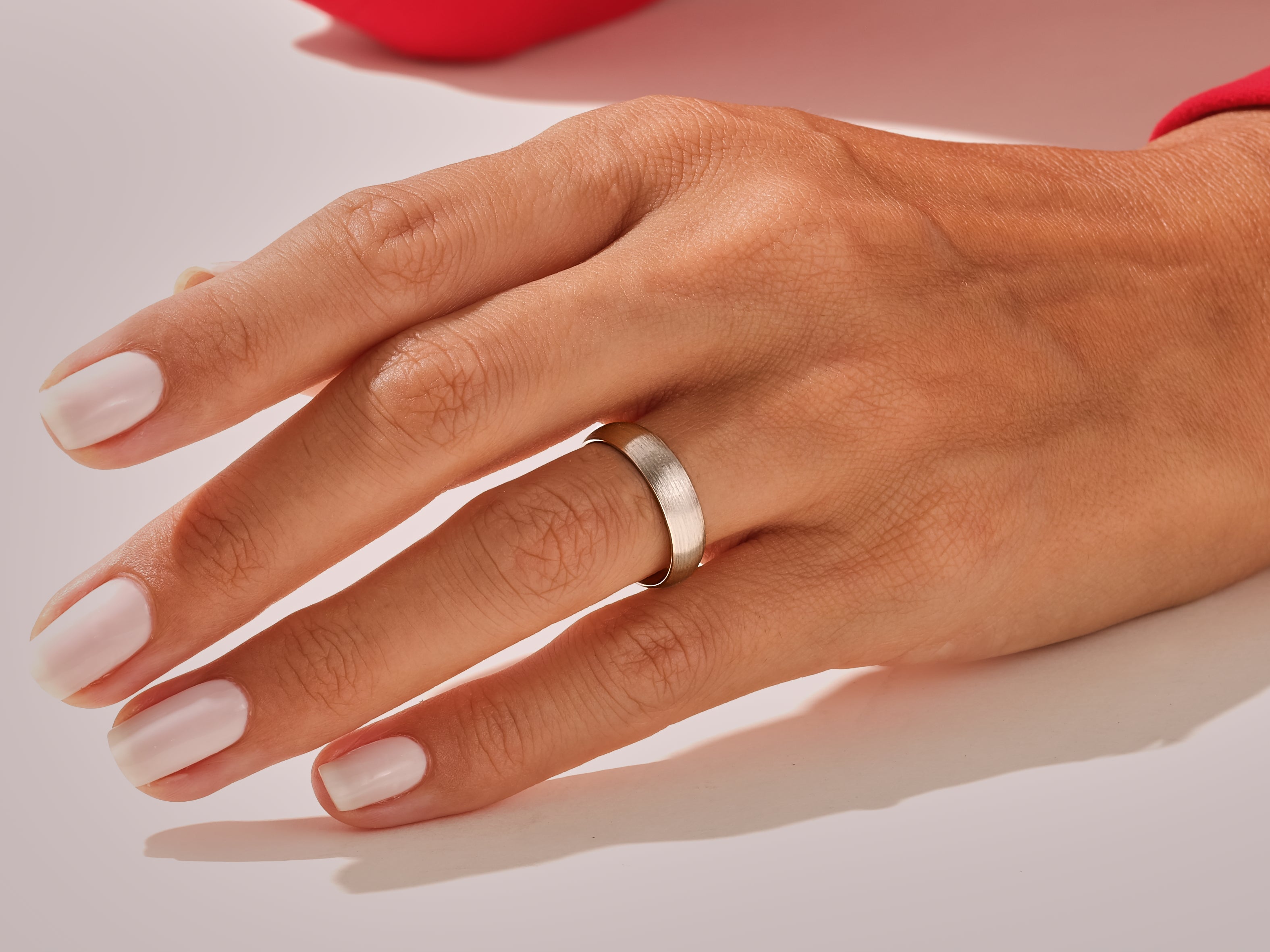 Silver band ring on a hand with manicured nails
