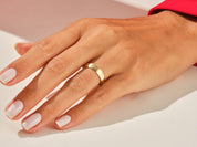 Gold band ring on a hand with manicured nails