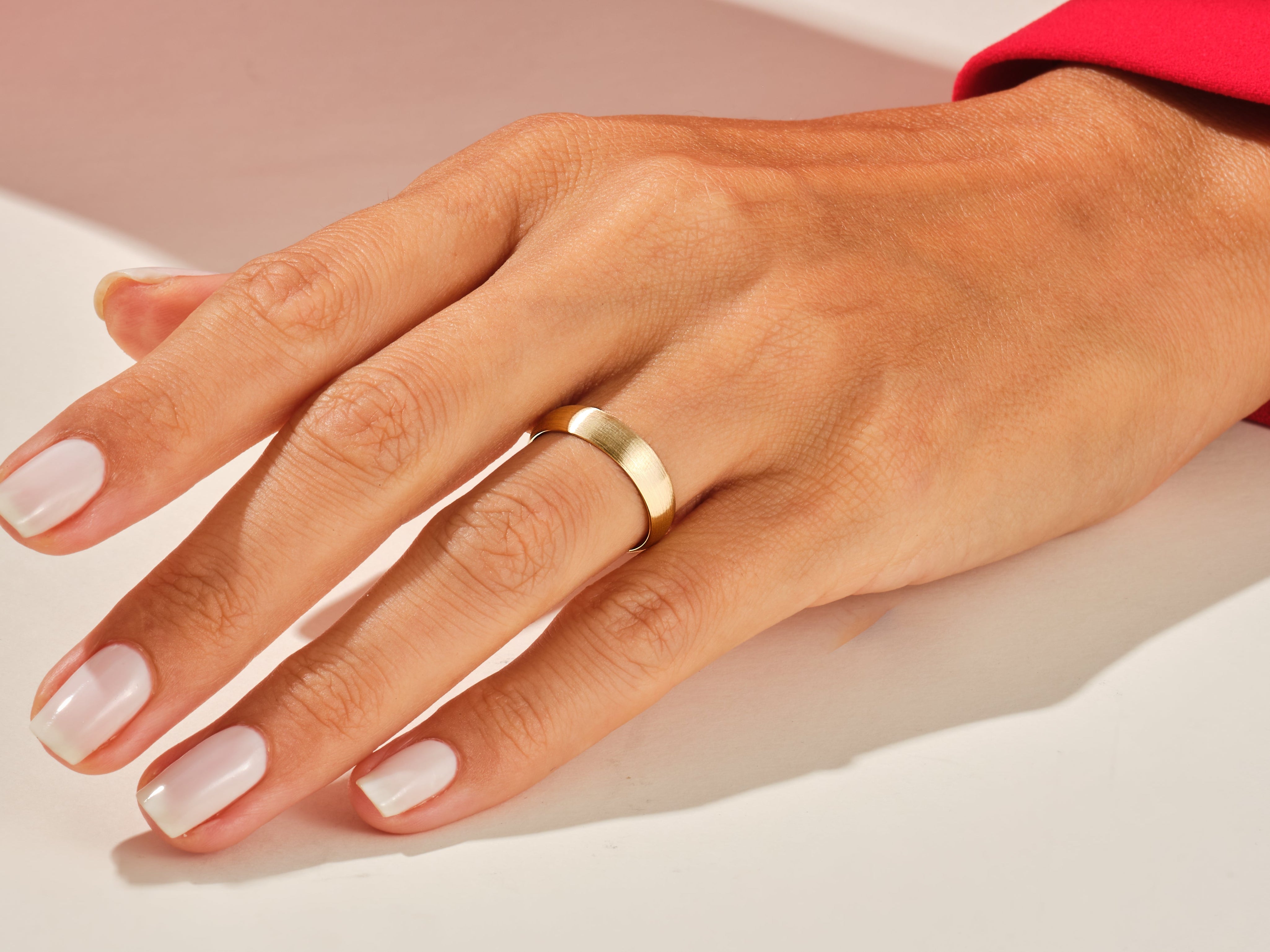 Gold band ring on a hand with manicured nails