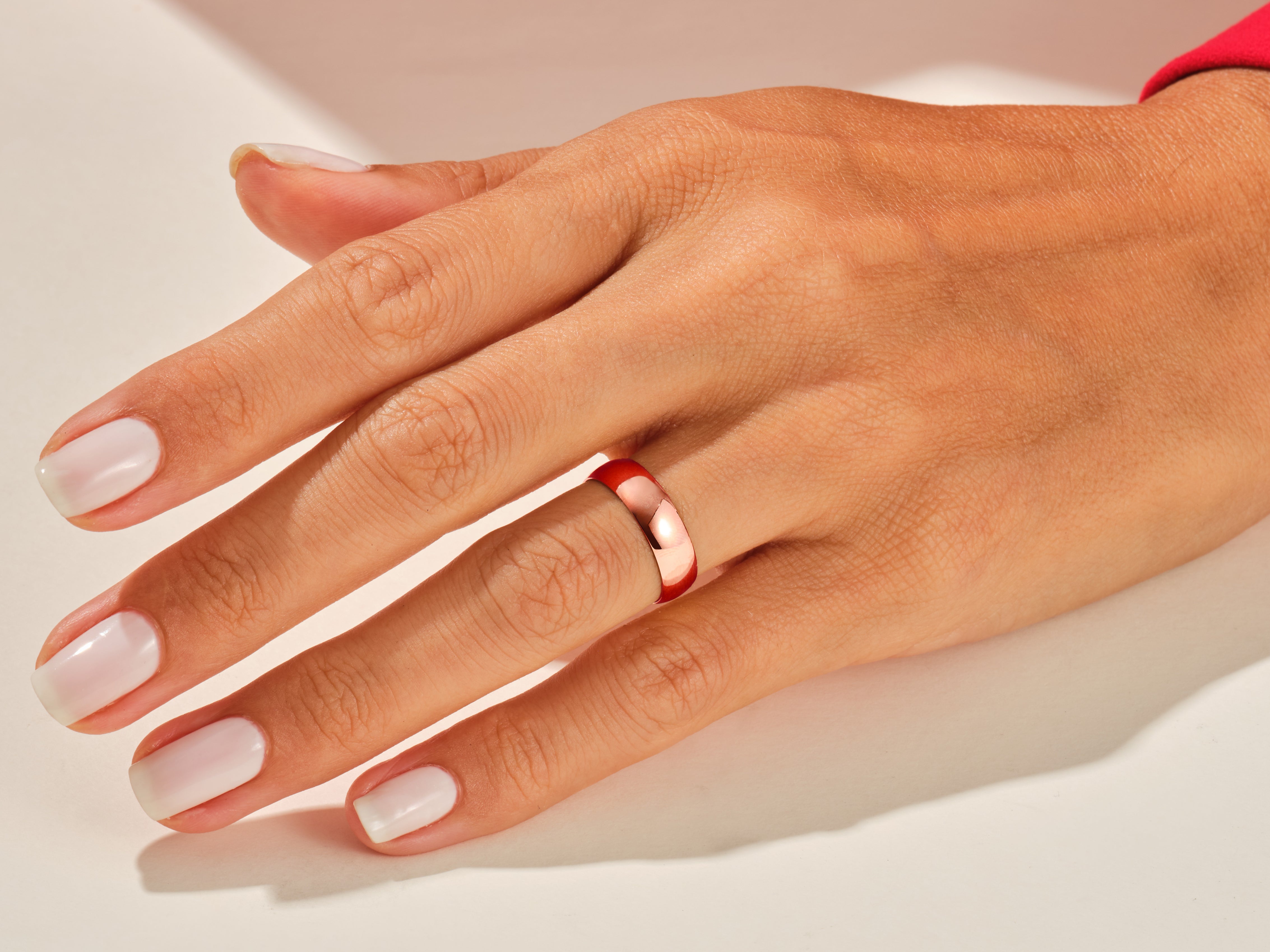 Rose gold band ring on a woman's finger, jewelry product photography