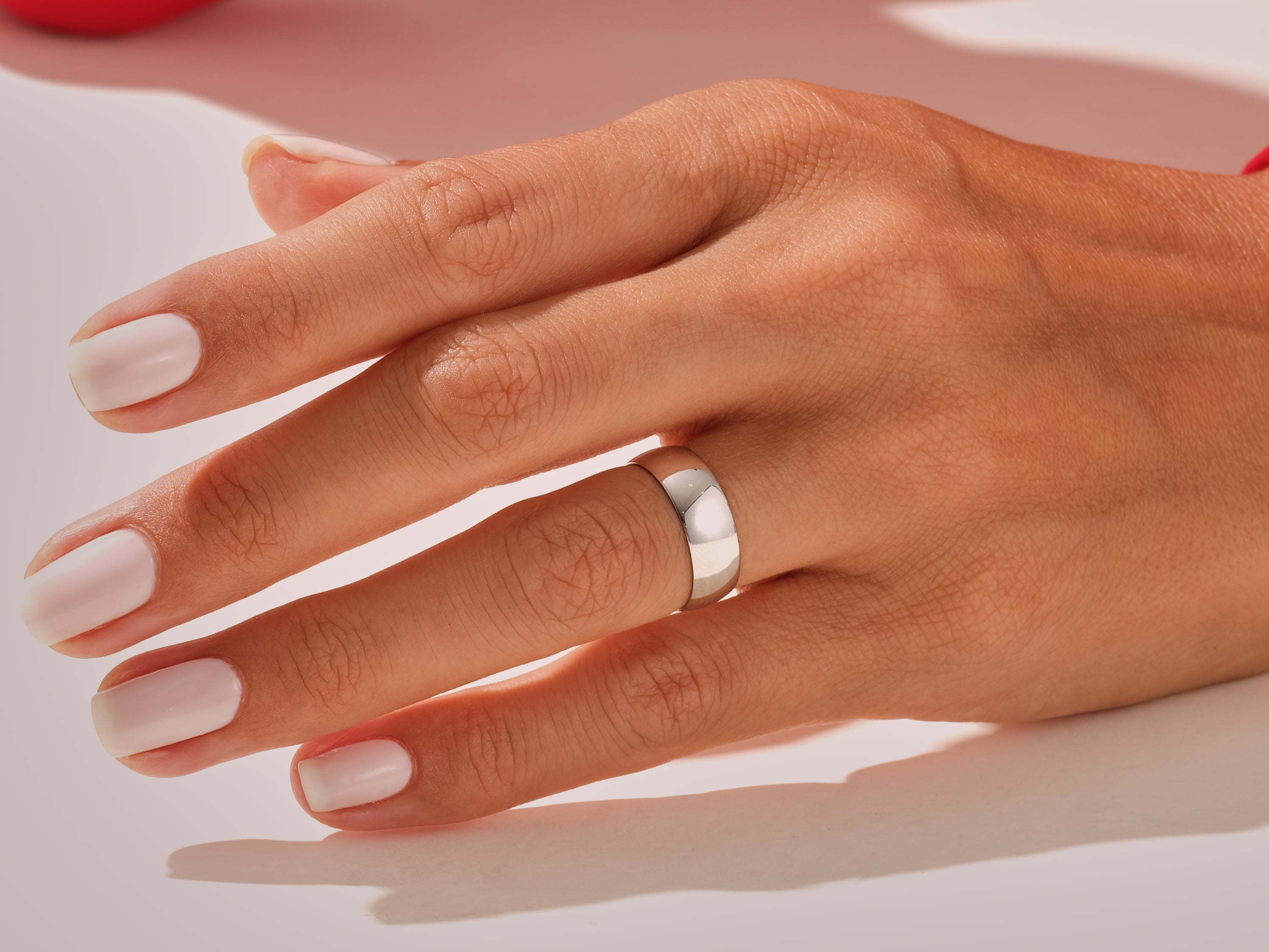 Silver band ring on a hand with manicured nails