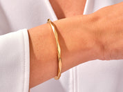 Gold twisted bangle bracelet on a woman's wrist