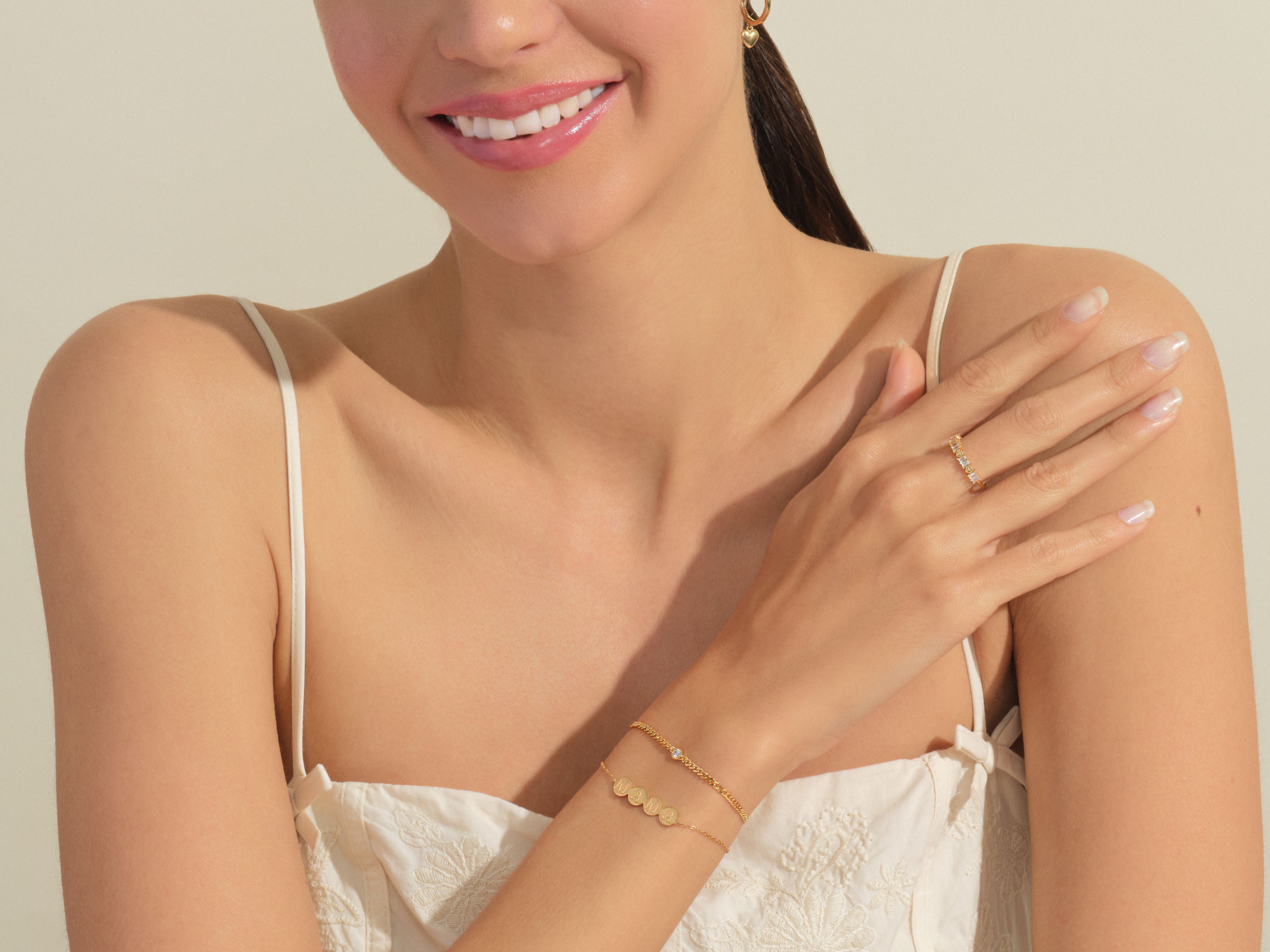 Gold jewelry on woman's arm, featuring a ring and bracelet