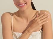 Gold jewelry on woman's arm, featuring a ring and bracelet