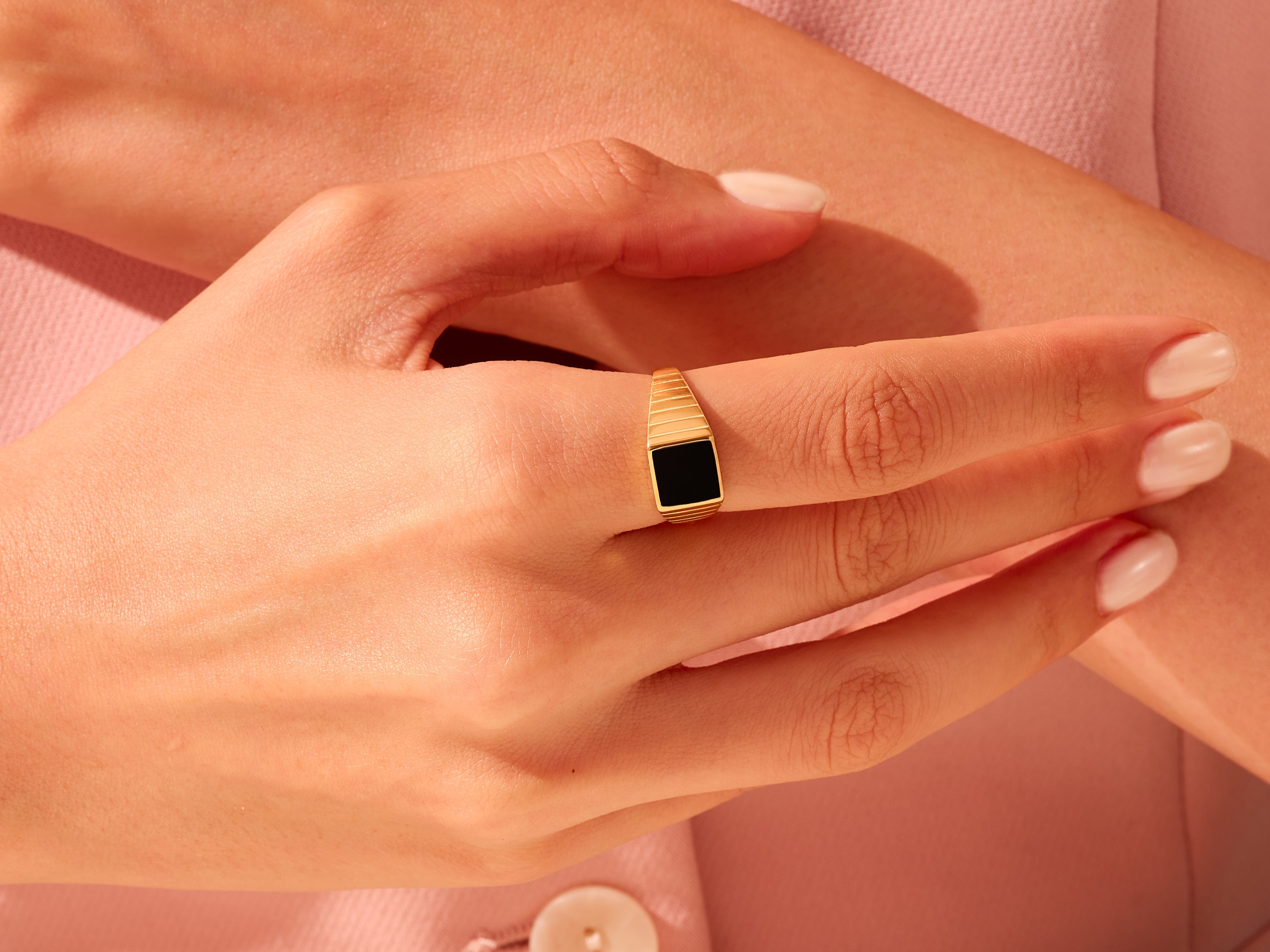 Gold signet ring with black onyx gemstone on a woman's finger