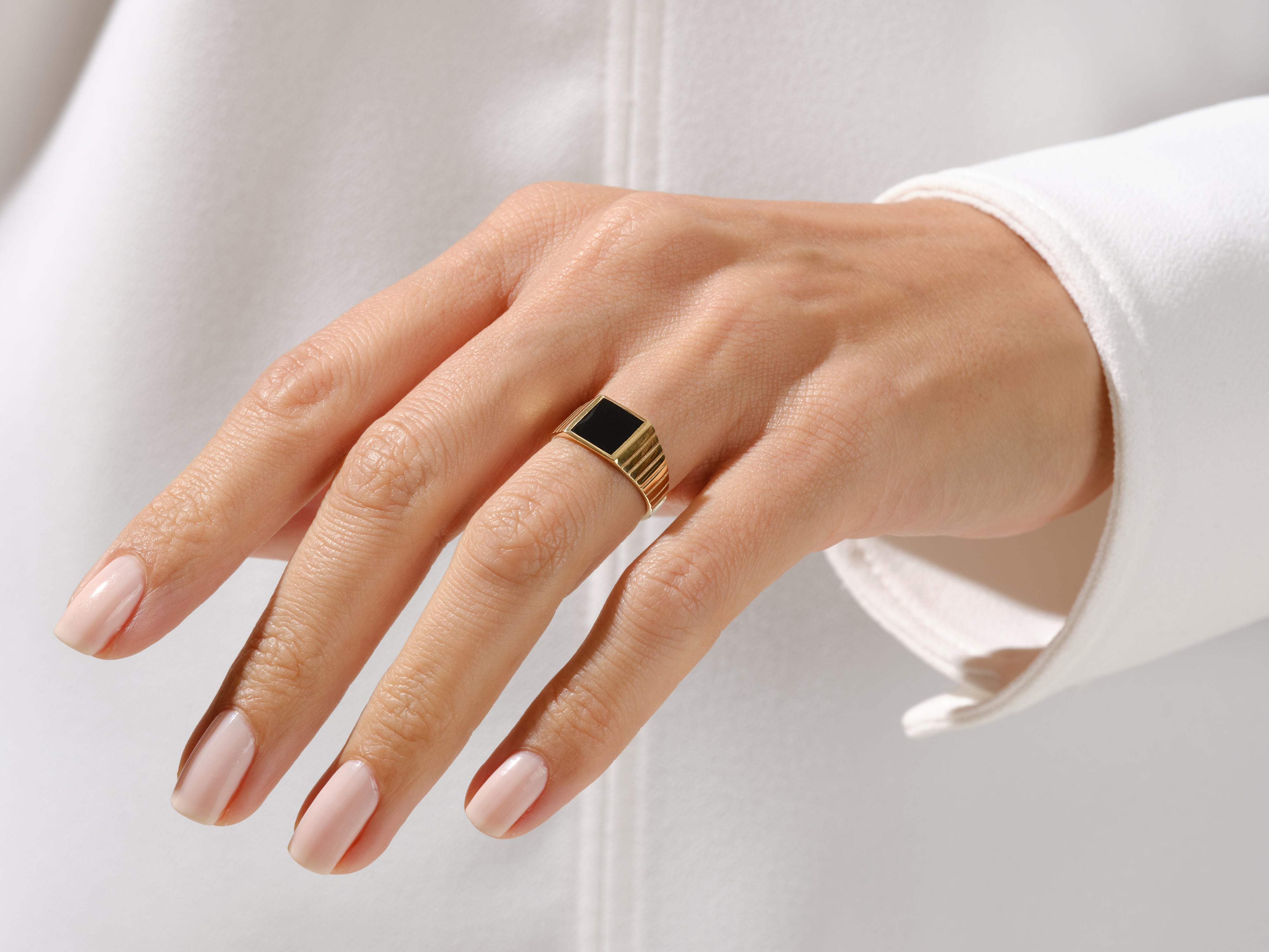 Gold signet ring with black onyx gemstone on a woman's hand