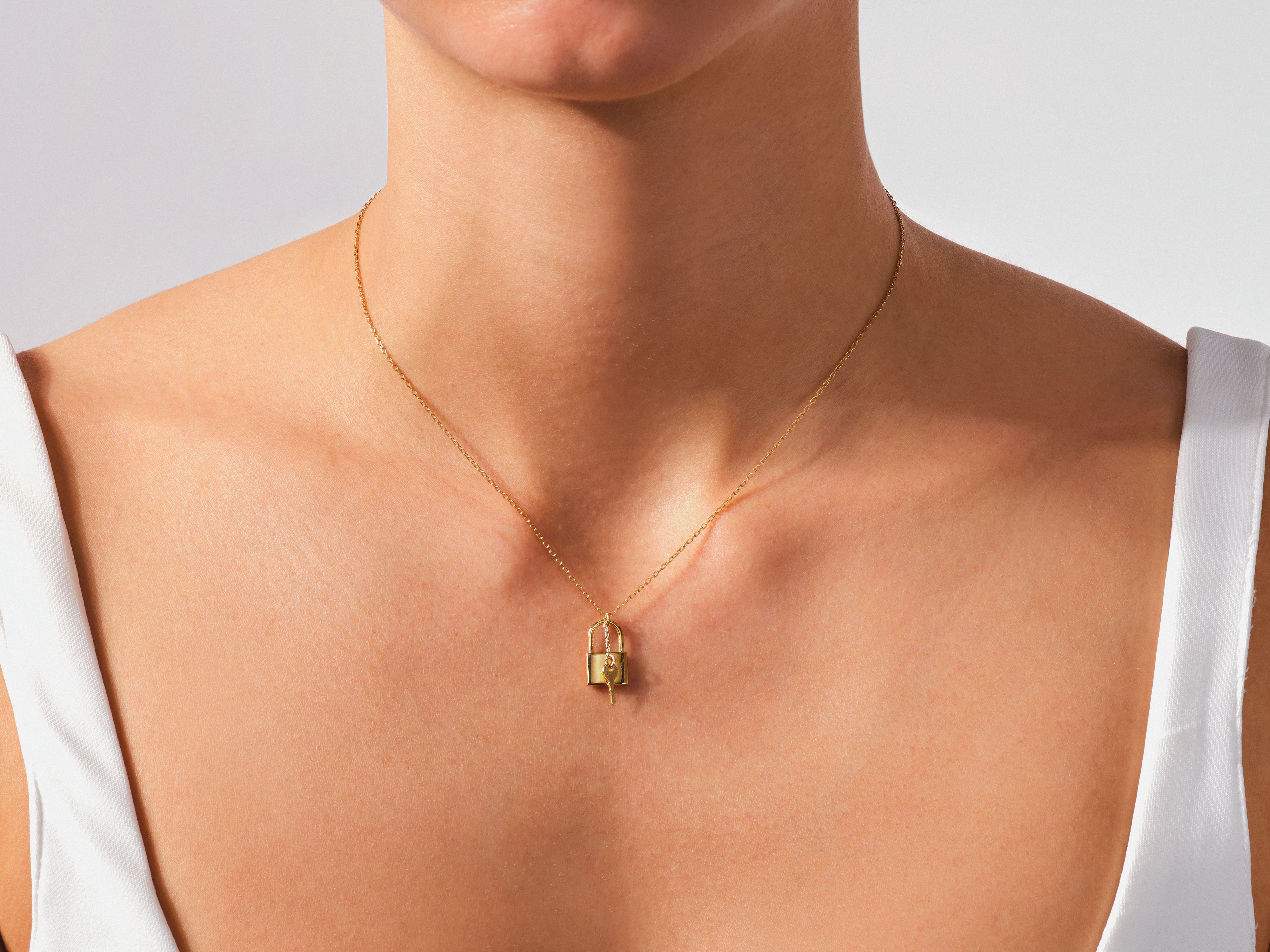 Gold padlock and key necklace on a woman's neck