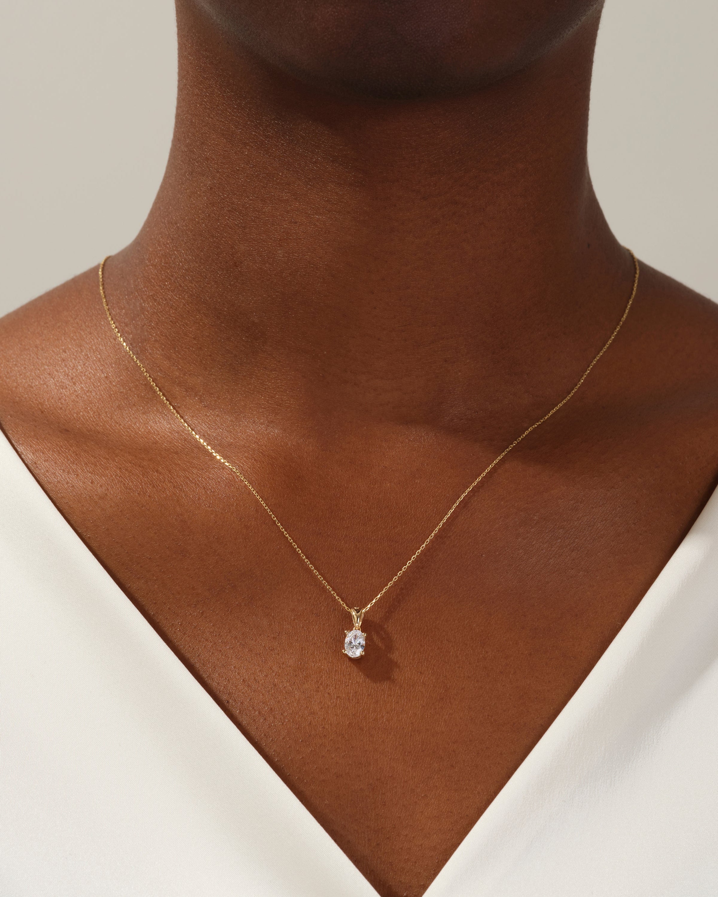 Gold oval diamond pendant necklace on a woman's neck