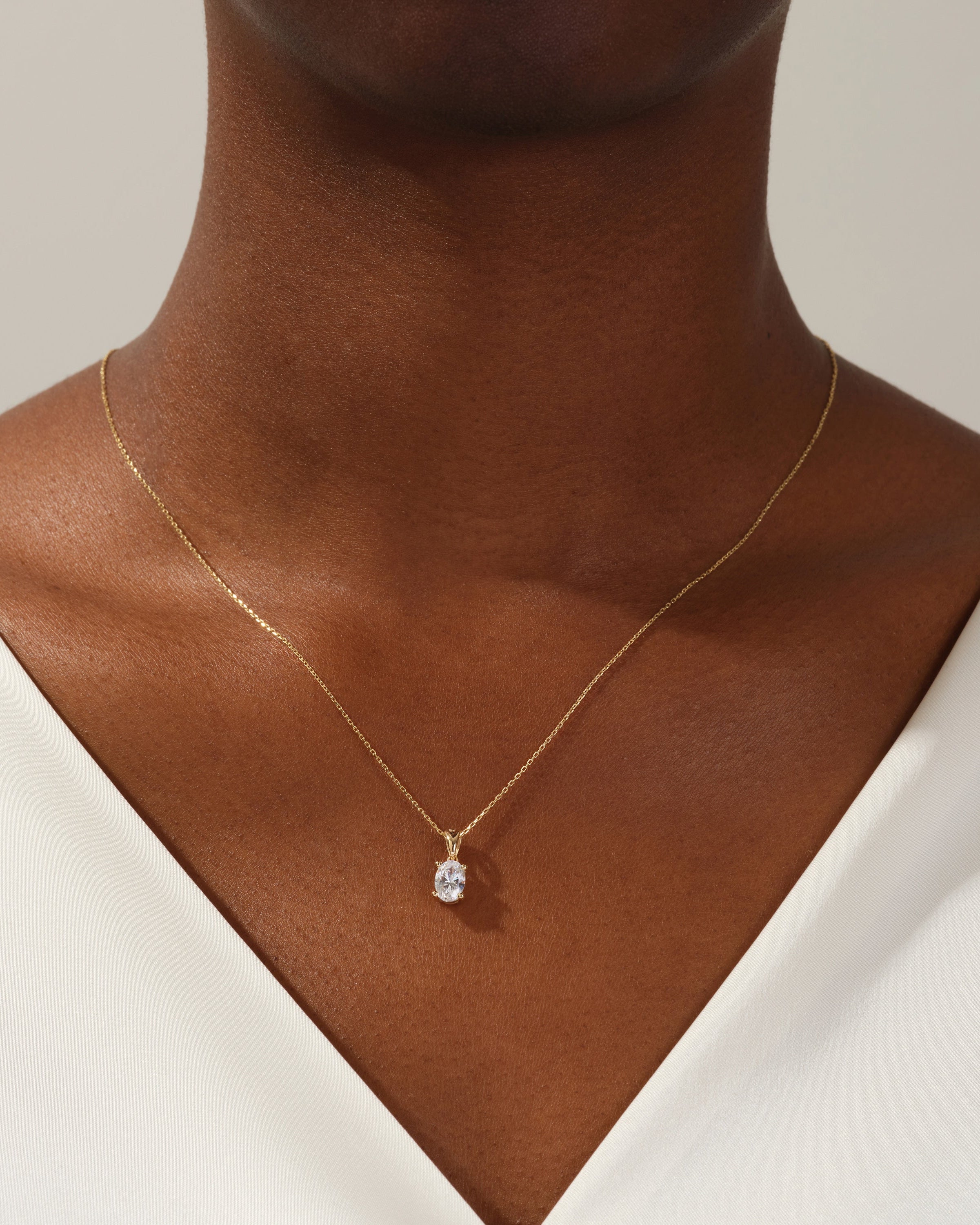 Gold oval diamond pendant necklace on a woman's neck
