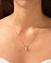 Gold necklace with emerald-cut diamond pendant on a woman's neck