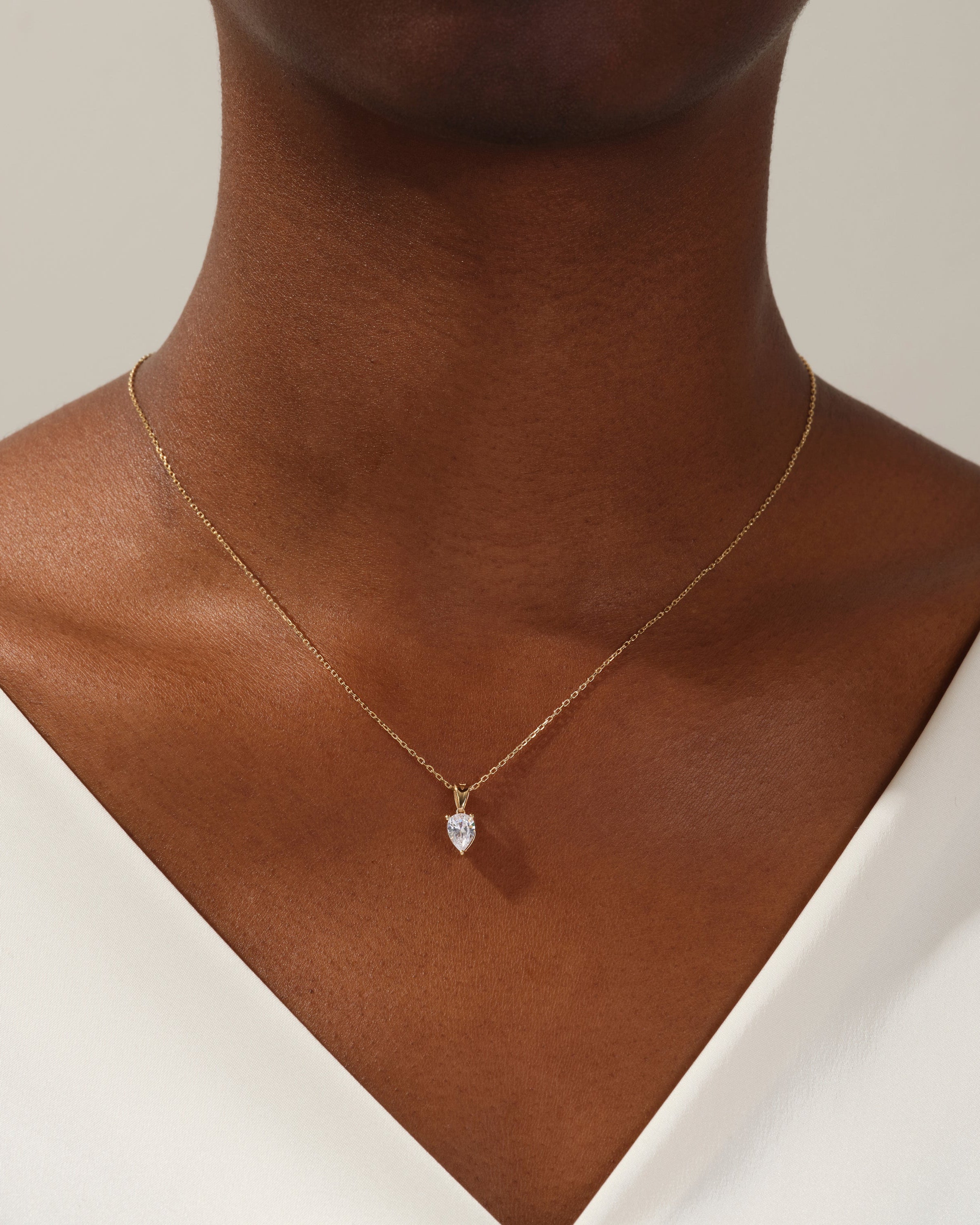 Gold pear-shaped diamond pendant necklace on a woman's neck