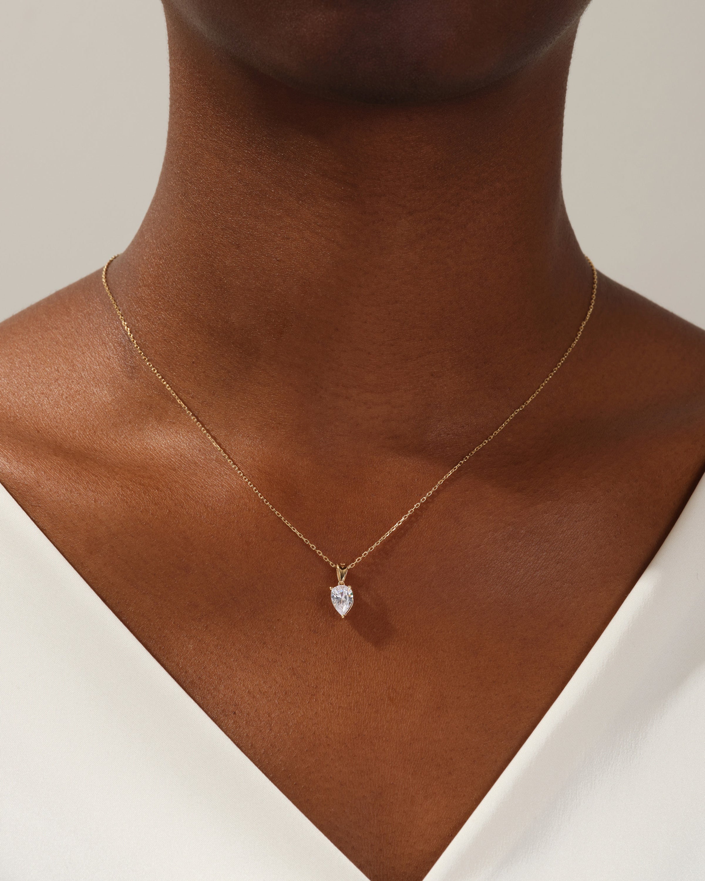 Gold necklace with pear-shaped diamond pendant on a woman's neck