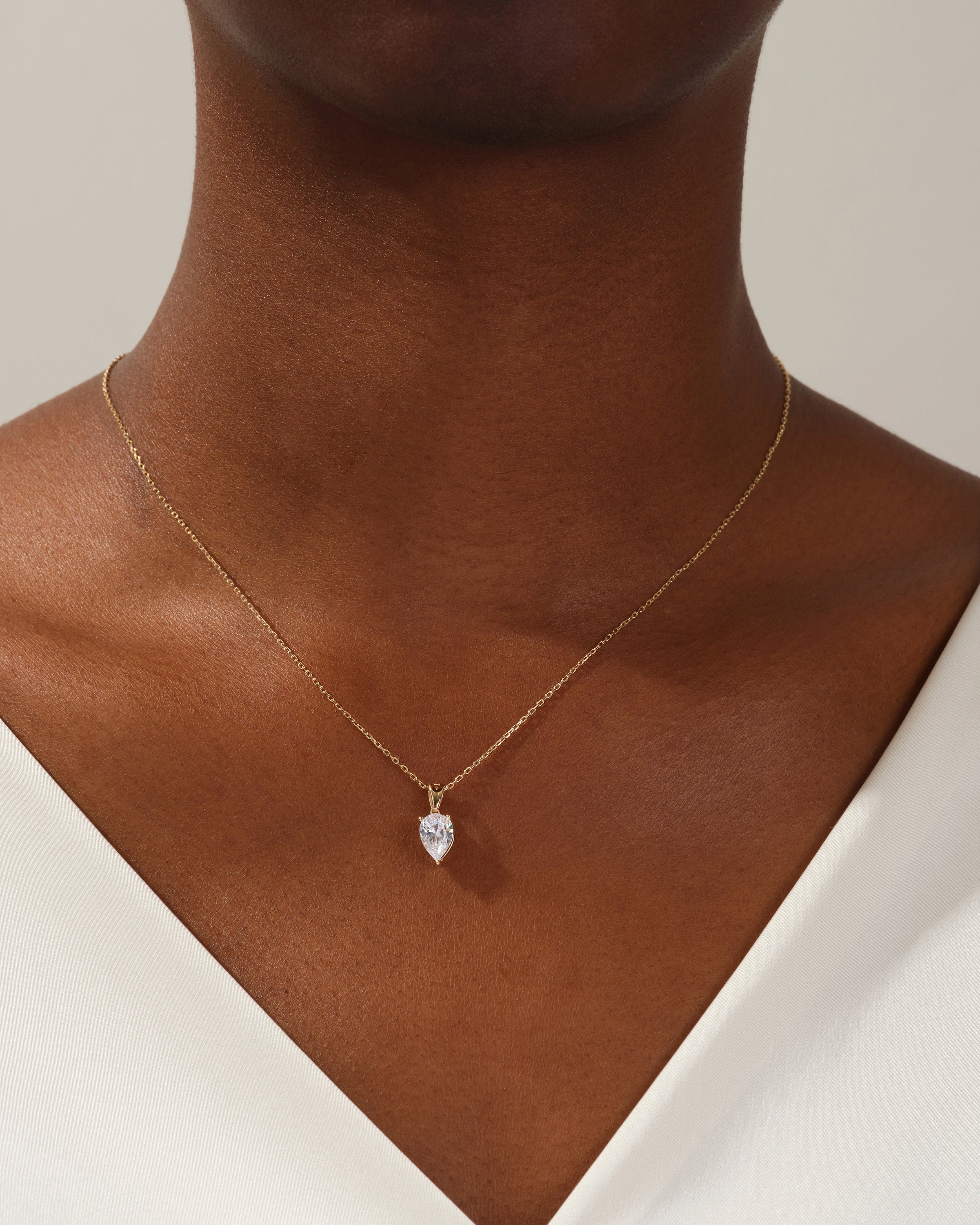 Gold necklace with pear-shaped diamond pendant on a woman's neck