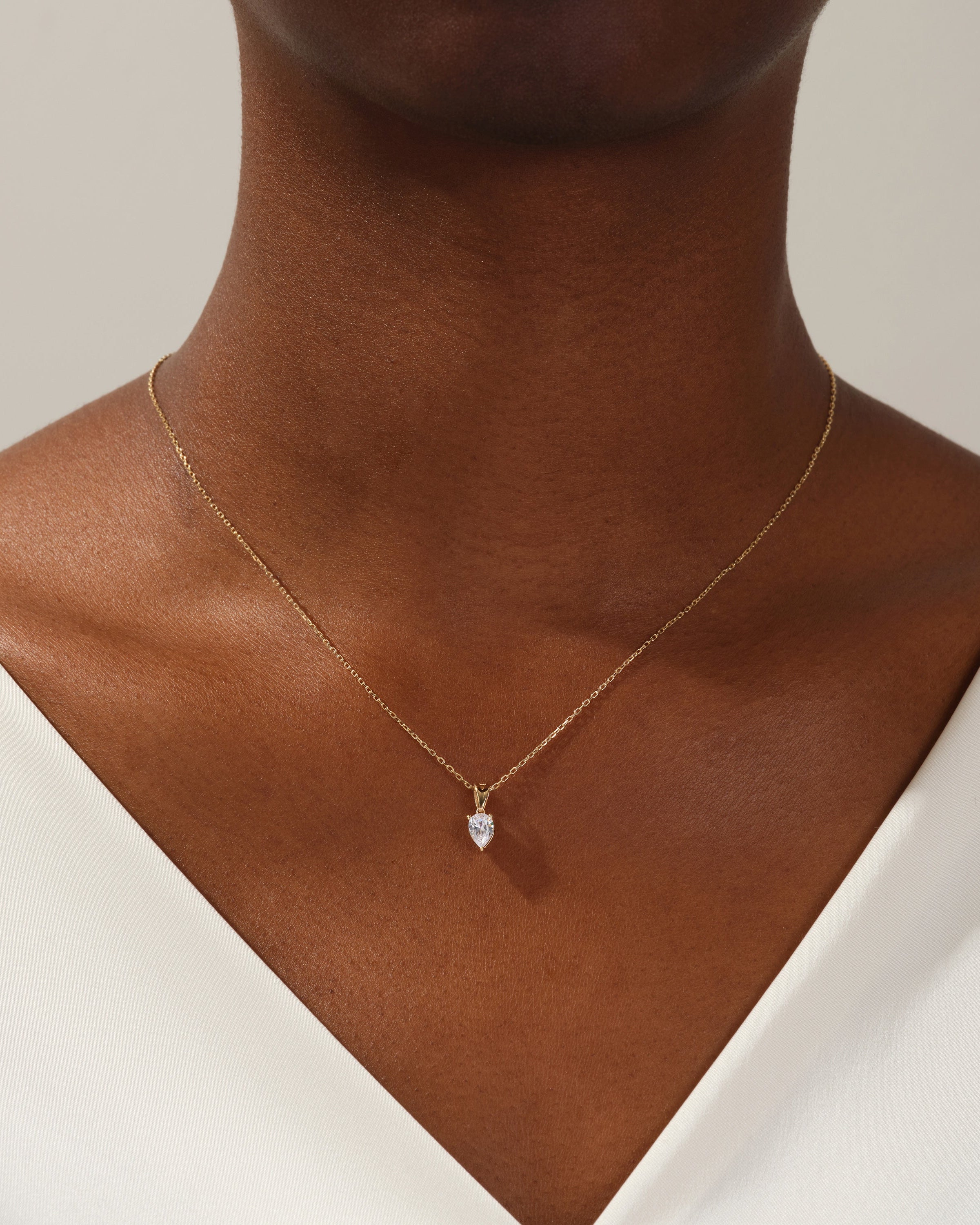 Gold necklace with pear-shaped diamond pendant on a woman's neck