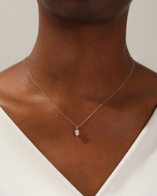 Gold necklace with pear-shaped diamond pendant on a woman's neck
