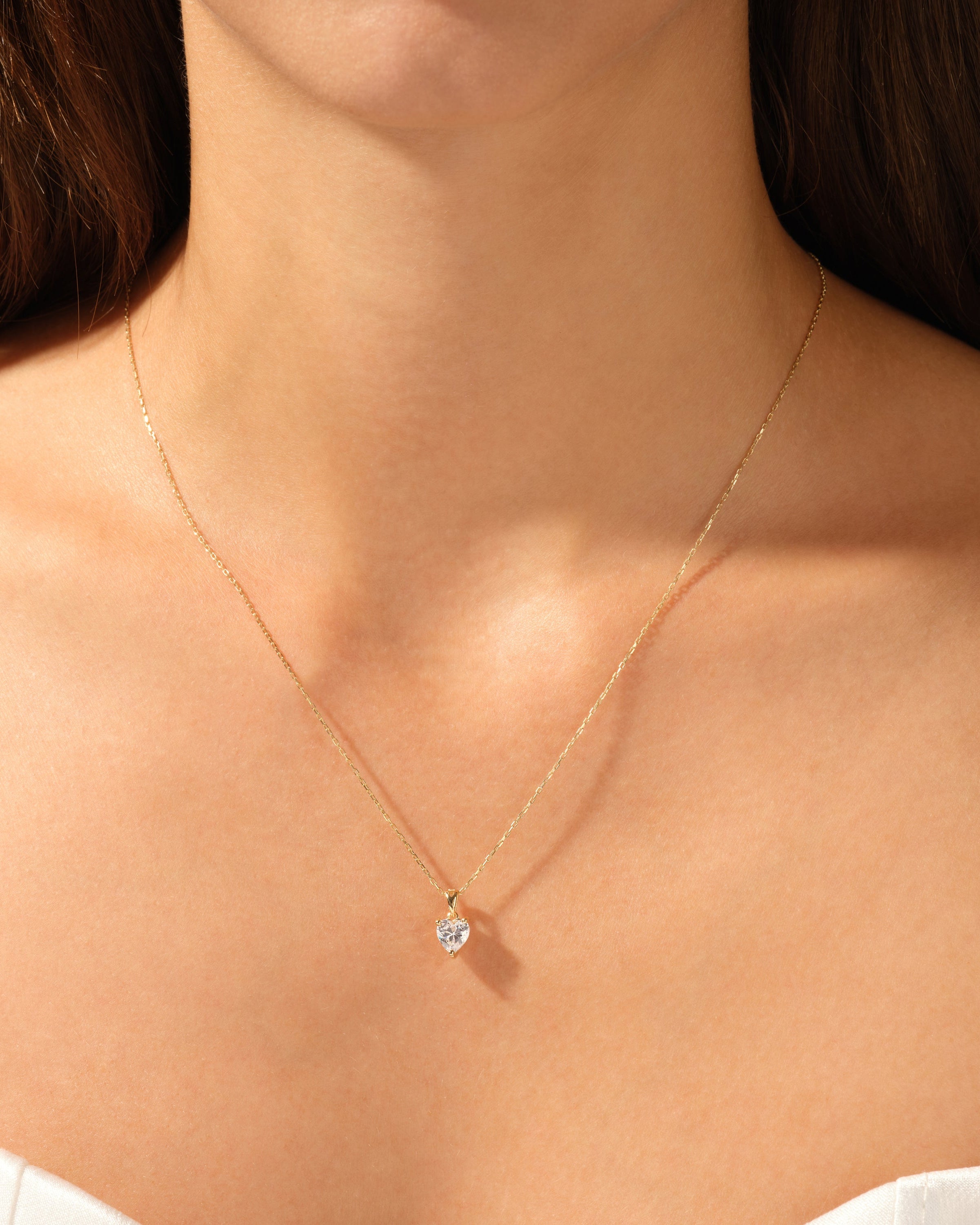 Gold heart necklace with diamond pendant on a woman's neck