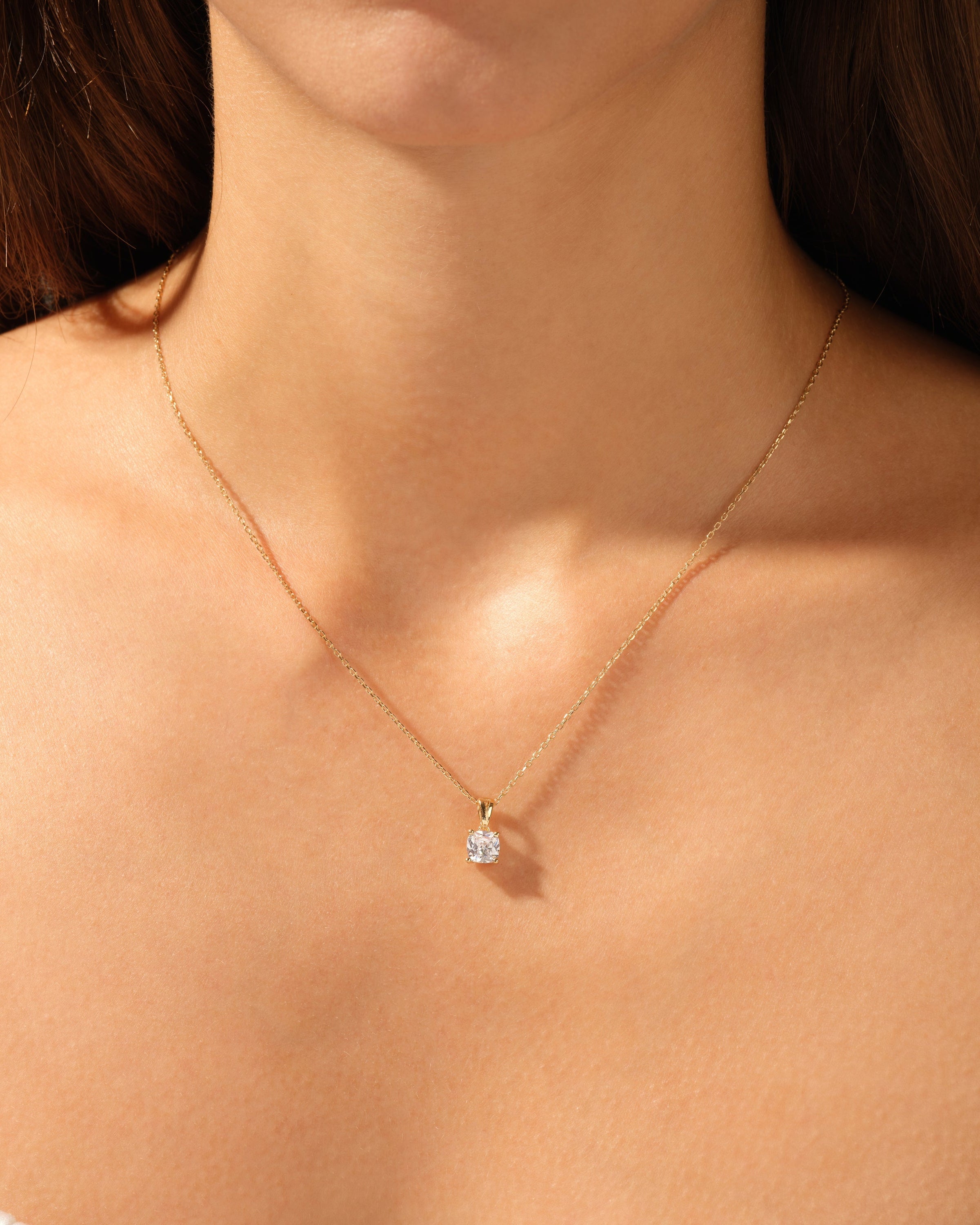 Gold diamond pendant necklace on a woman's neck