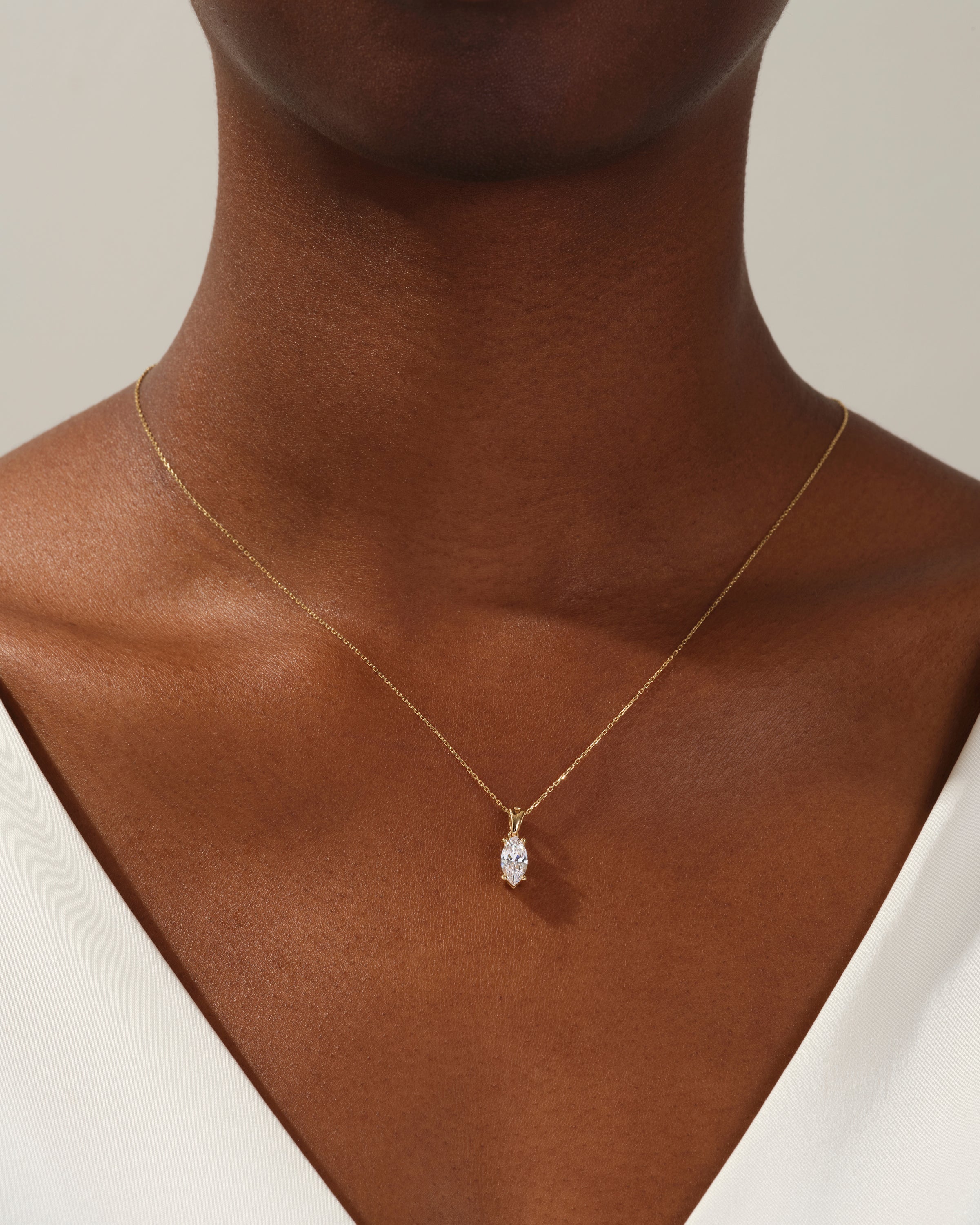 Gold necklace with marquise diamond pendant on woman's neck