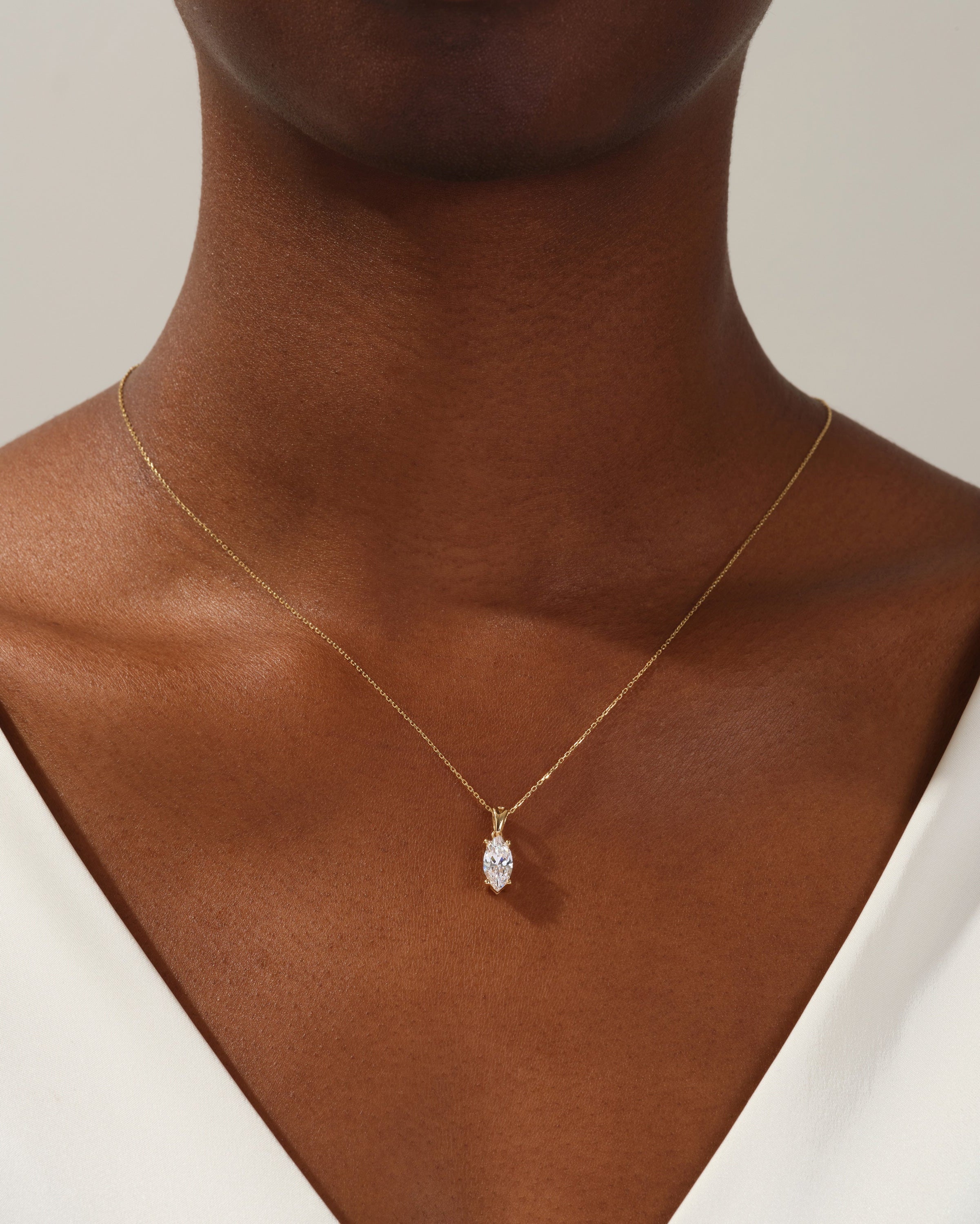 Gold marquise diamond pendant necklace on a woman's neck