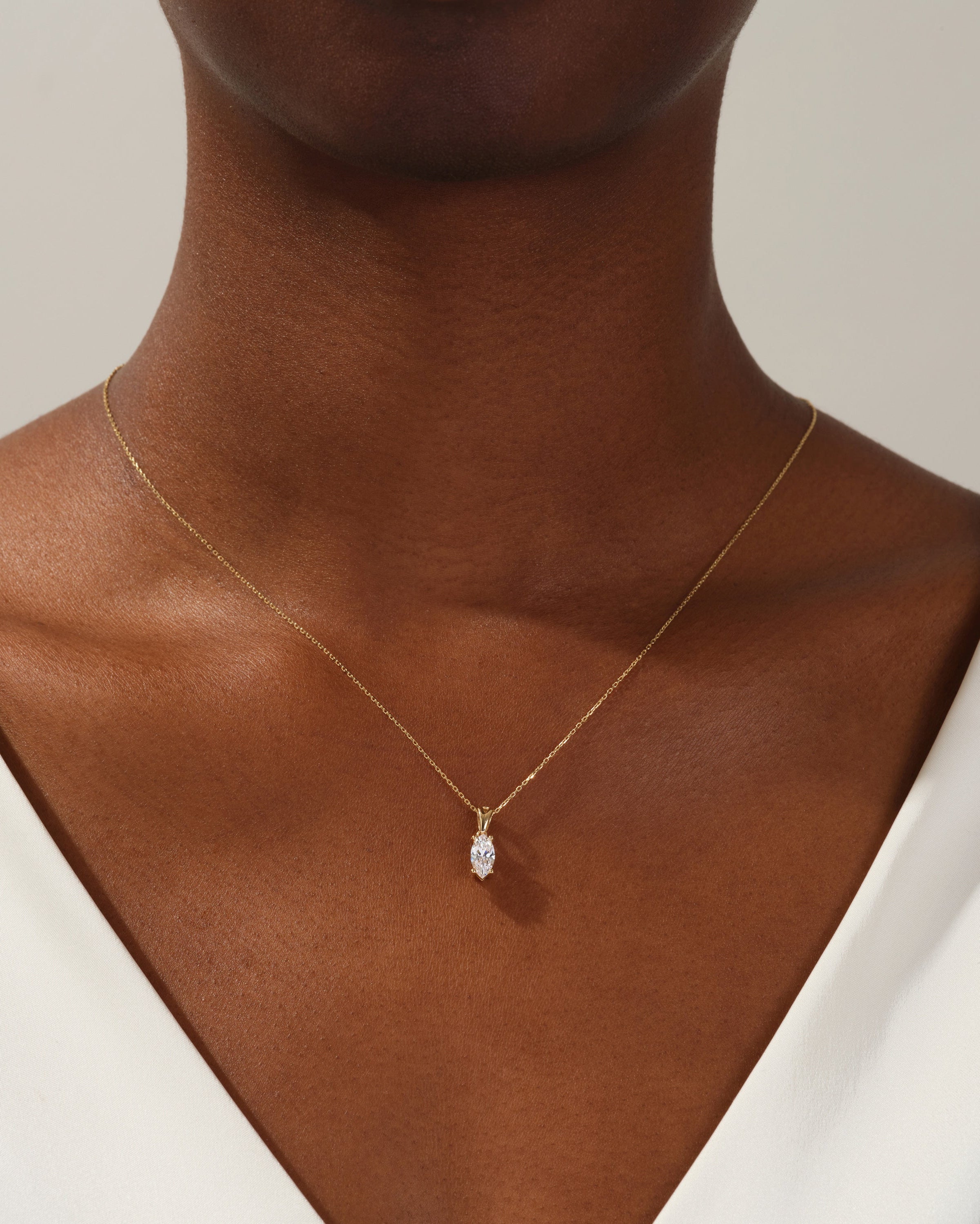 Gold necklace with marquise diamond pendant on woman's neck