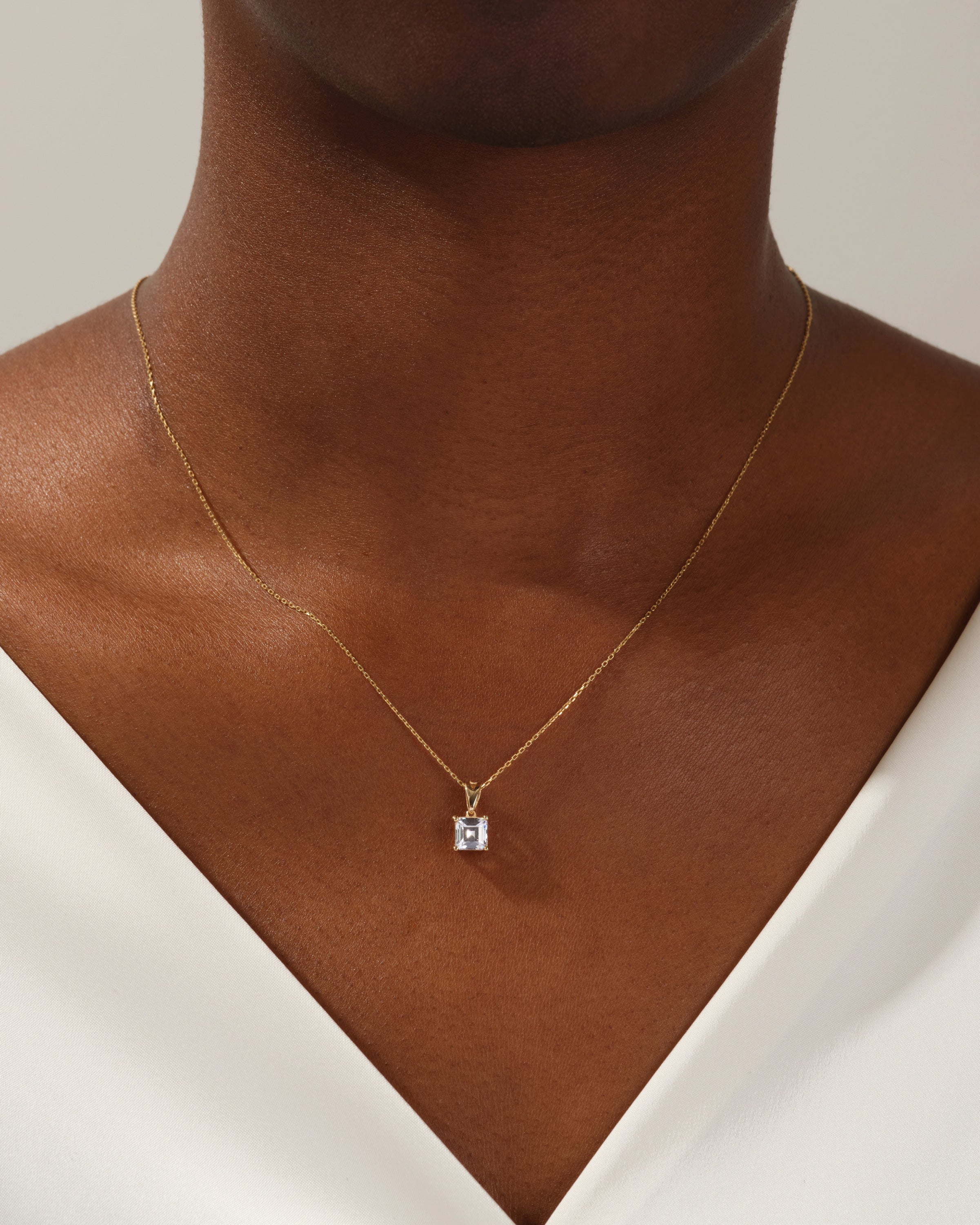 Gold necklace with square gemstone pendant on model