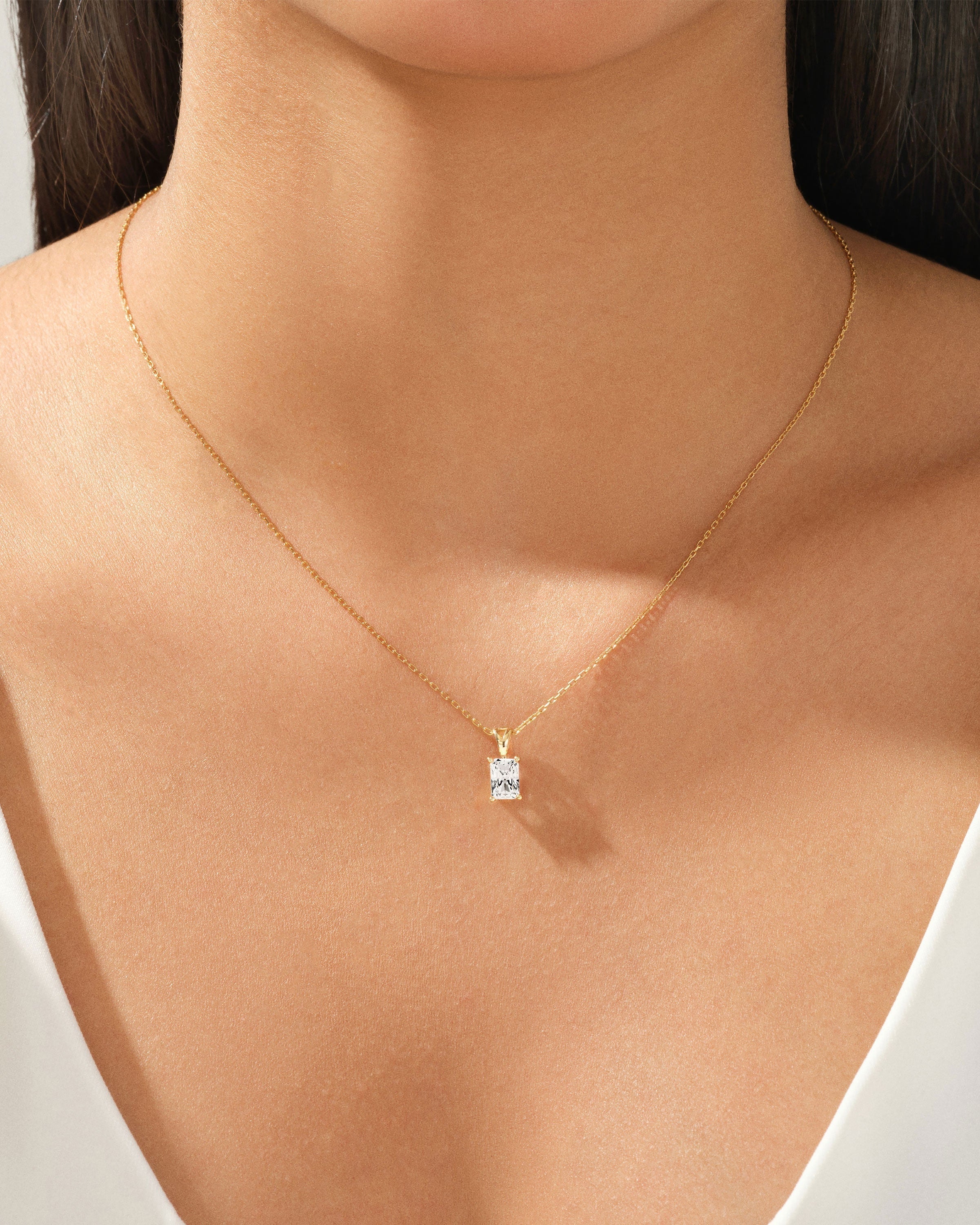 Gold necklace with a radiant diamond pendant on a woman's neck