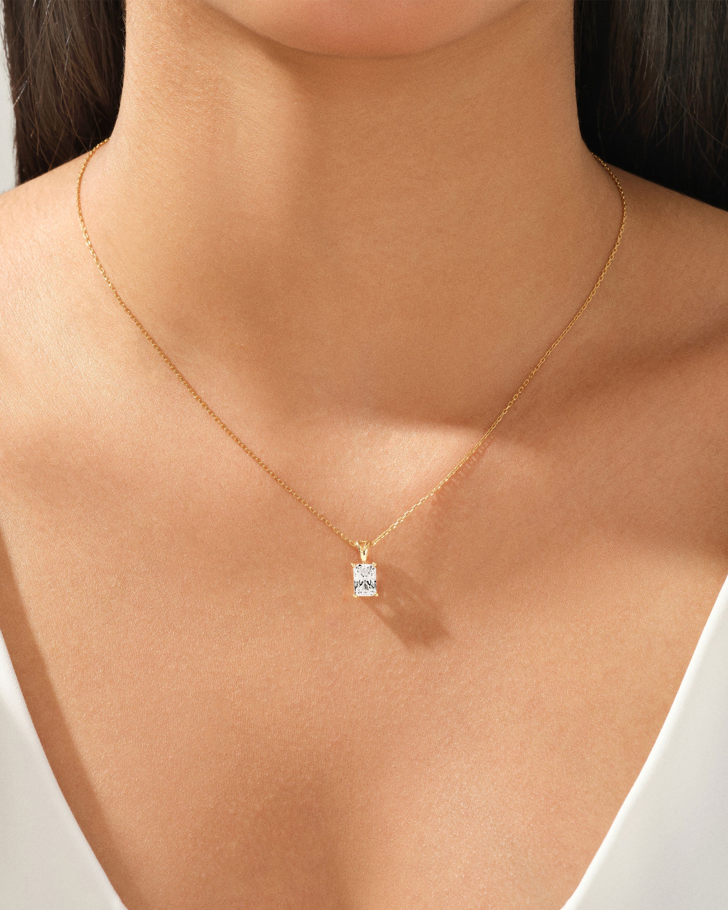 Gold necklace with a radiant diamond pendant on a woman's neck