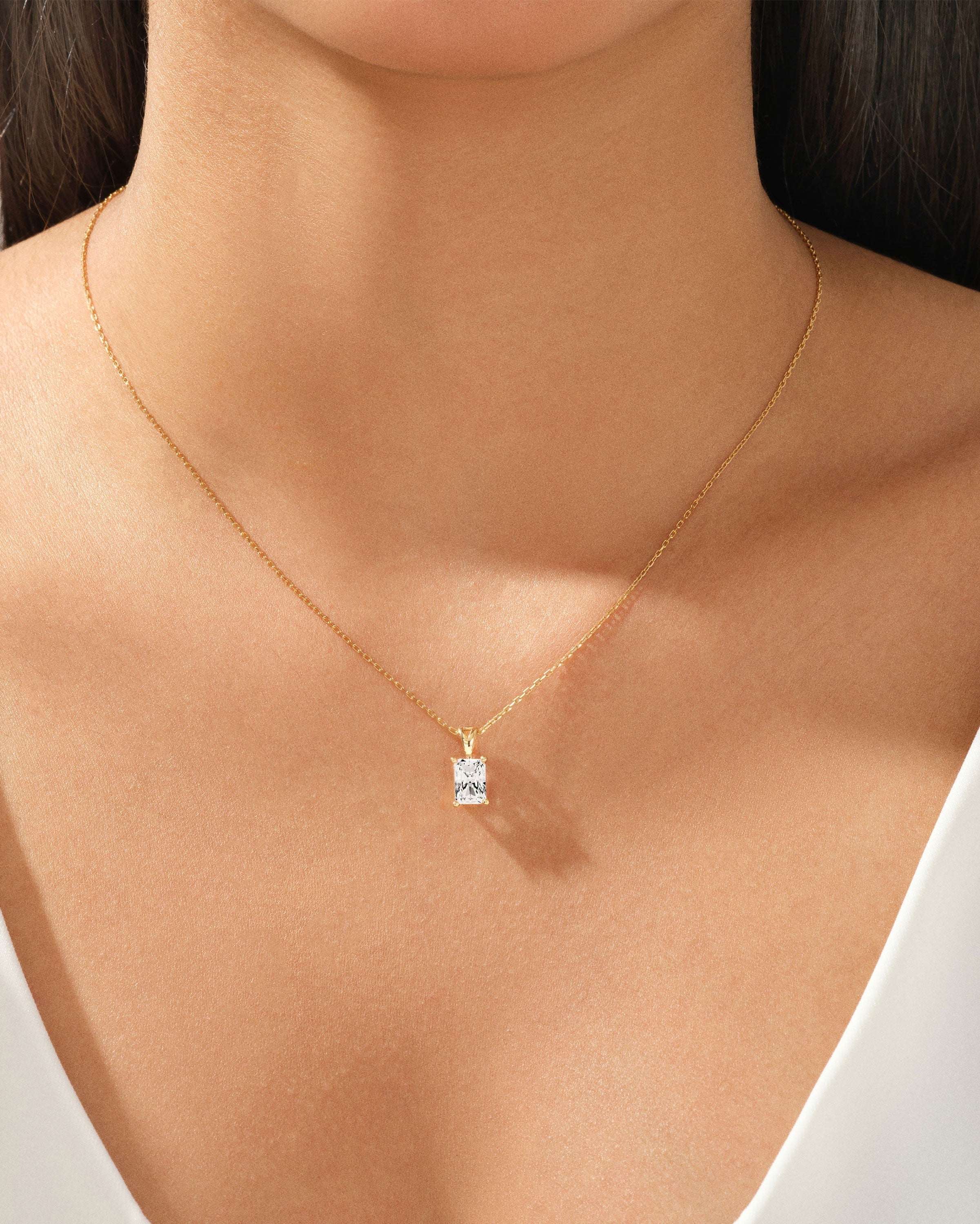 Gold necklace with a radiant diamond pendant on a woman's neck