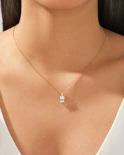 Gold necklace with a square-cut diamond pendant on a woman's neck