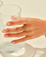 Gold snake ring on hand near elegant glassware