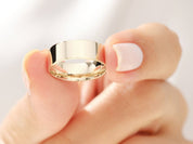 Gold band ring held by a manicured hand, jewelry product