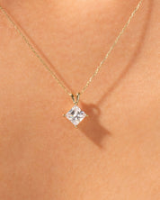 Gold necklace with princess cut diamond pendant on skin
