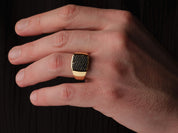 Gold ring with black diamonds on a man's finger